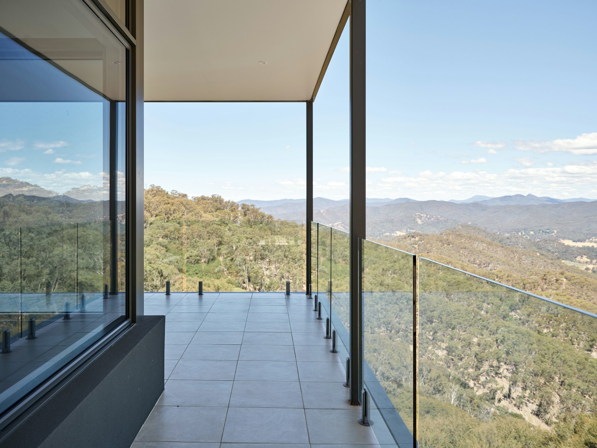 Frameless glass railing on an outdoor terrace with a view